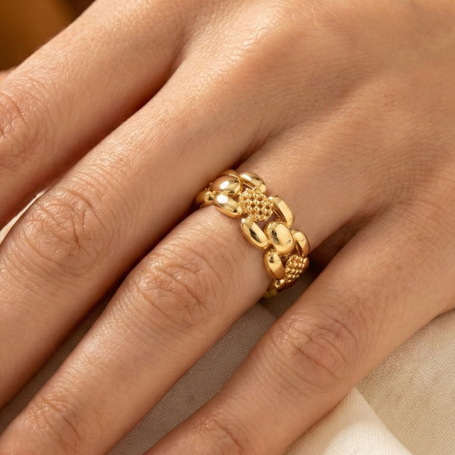 Gold ring on a hand with a neutral background