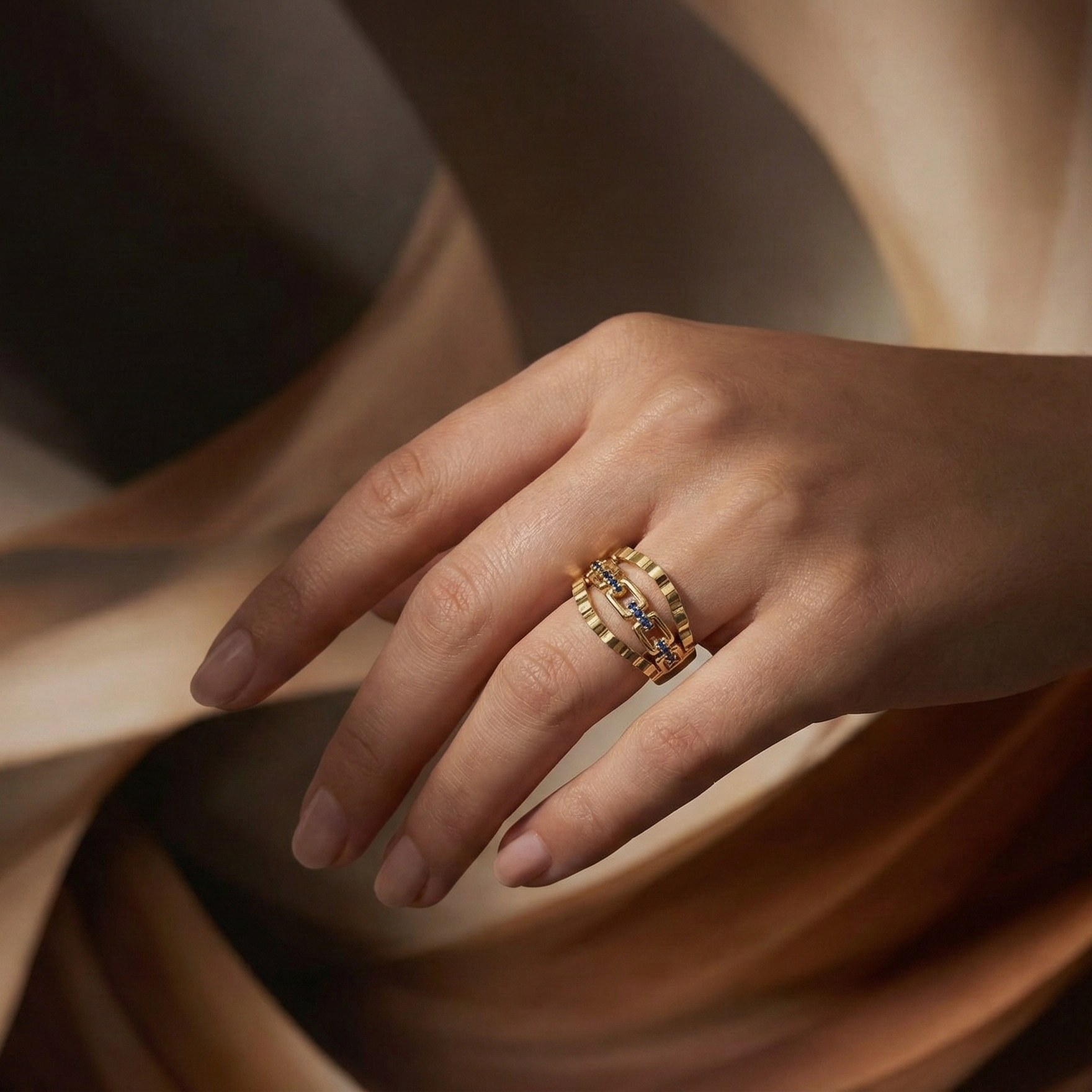 Hand wearing a gold ring with a diamond on a soft fabric background